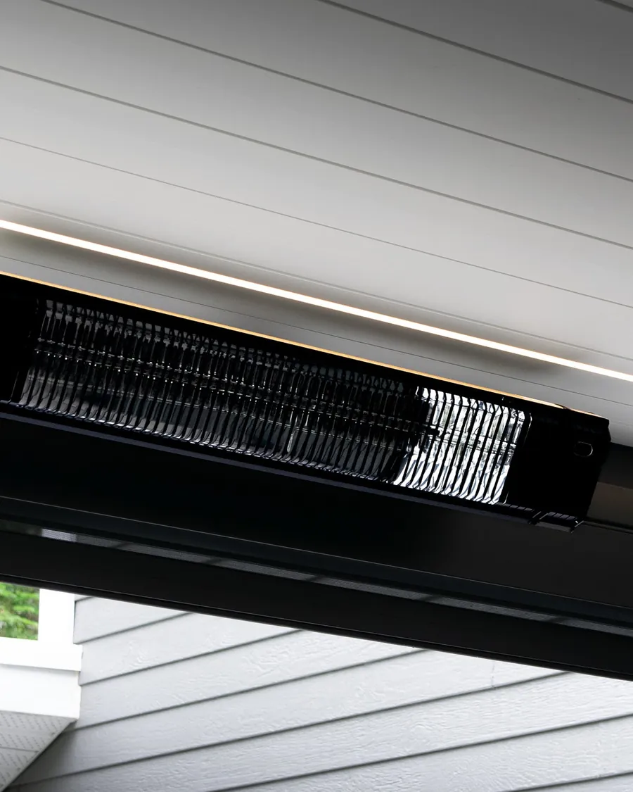 Chauffe-terrasse électrique noir fixé sous la poutre d’une pergola, bandeau d’éclairage DEL de la structure juste au-dessus