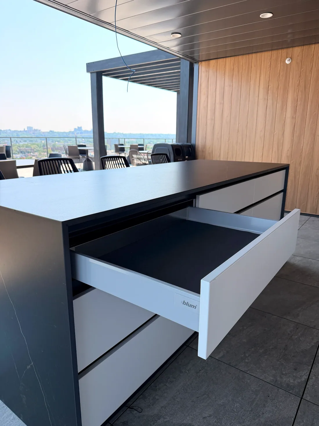 Outdoor kitchen cabinet drawer pulled open on its Blum® runner, beneath a black sintered stone countertop