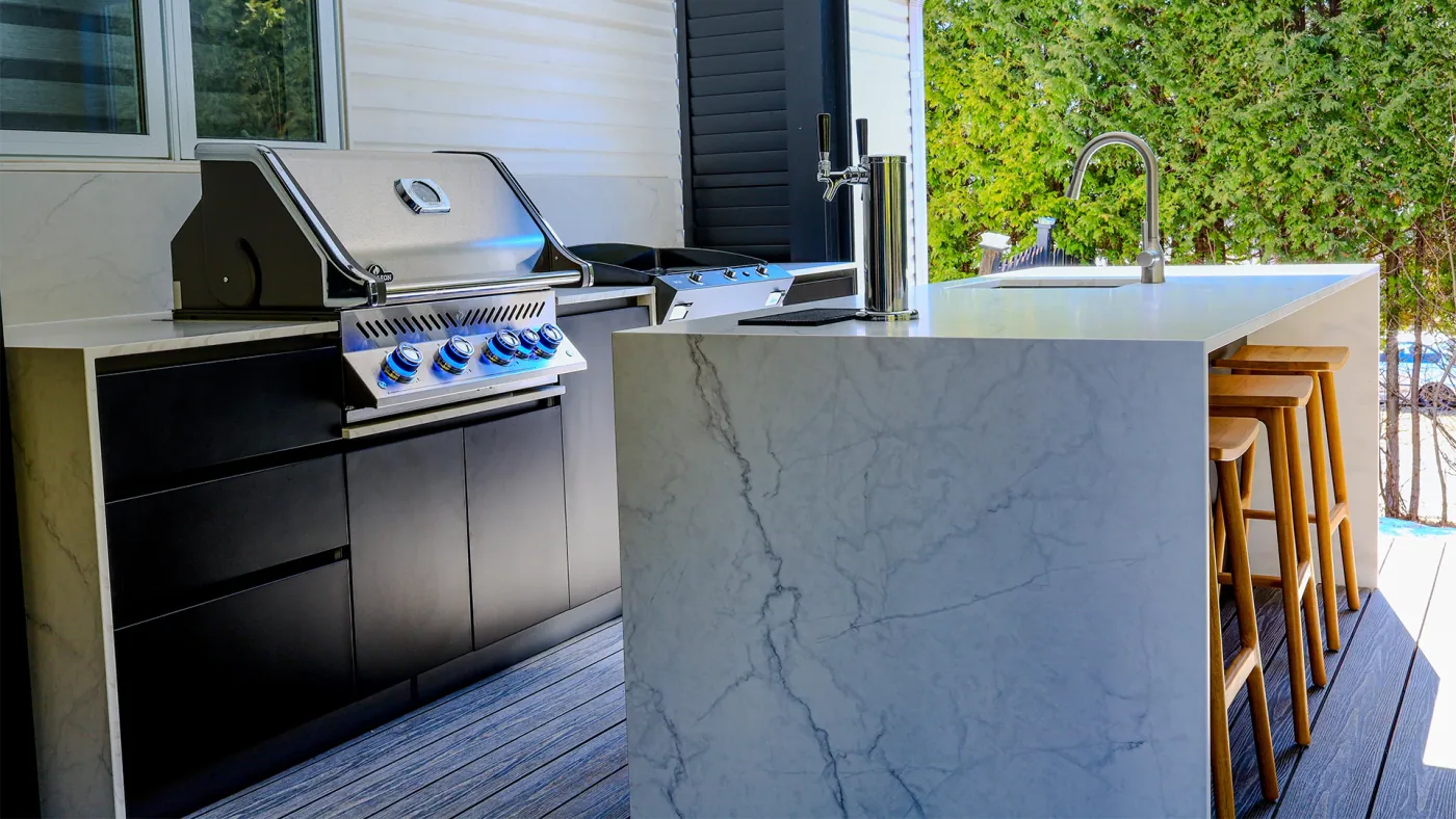 Outdoor kitchen island with a white veined Orastone® sintered stone countertop and waterfall edge