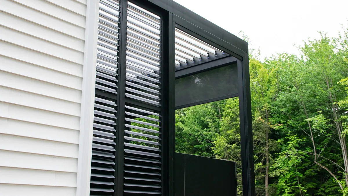 Aluminum privacy wall with adjustable louvres mounted on a pergola