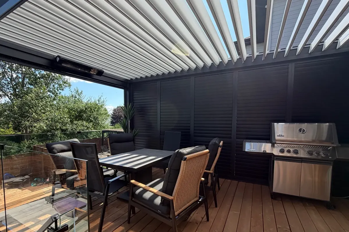 Toit-terrasse avec cuisine extérieure, murs d'intimité en persiennes noires fermées derrière le barbecue