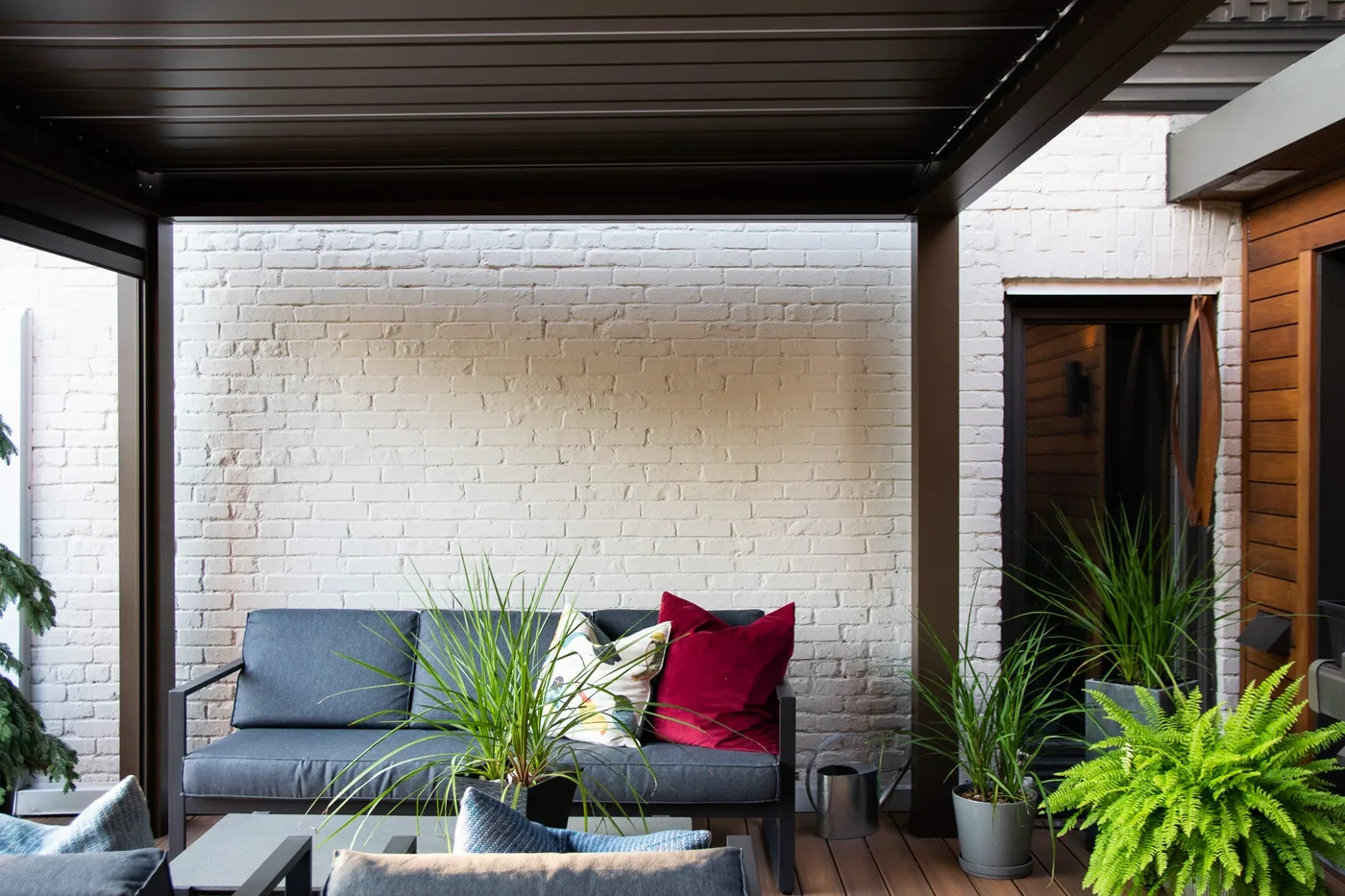 Pergola bioclimatique Provence adossée à une résidence, au-dessus d’une terrasse et d’un jardin