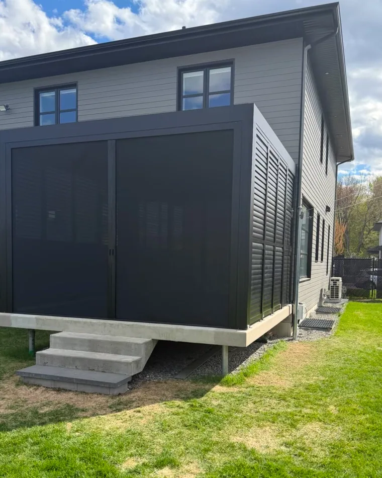 Horizontal solar shade in a double opening, drawn across the whole bay of a pergola against a house: the two panels meeting at the centre, the louvred privacy wall at the end and the concrete slab