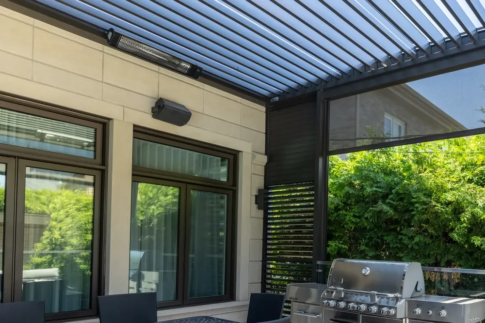 Lames orientables et poutre en aluminium d’une pergola bioclimatique, chauffe-terrasse électrique fixé au mur et mur d’intimité à lames, au-dessus d’une terrasse