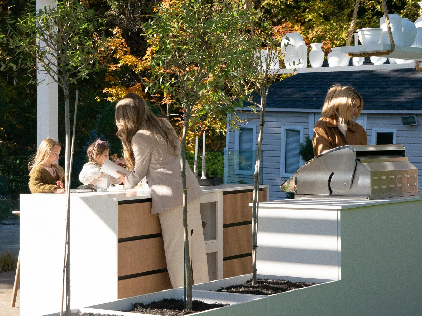 Cuisine extérieure sur mesure en acier inoxydable blanc, tiroirs rehaussés de chêne et grill Napoleon.