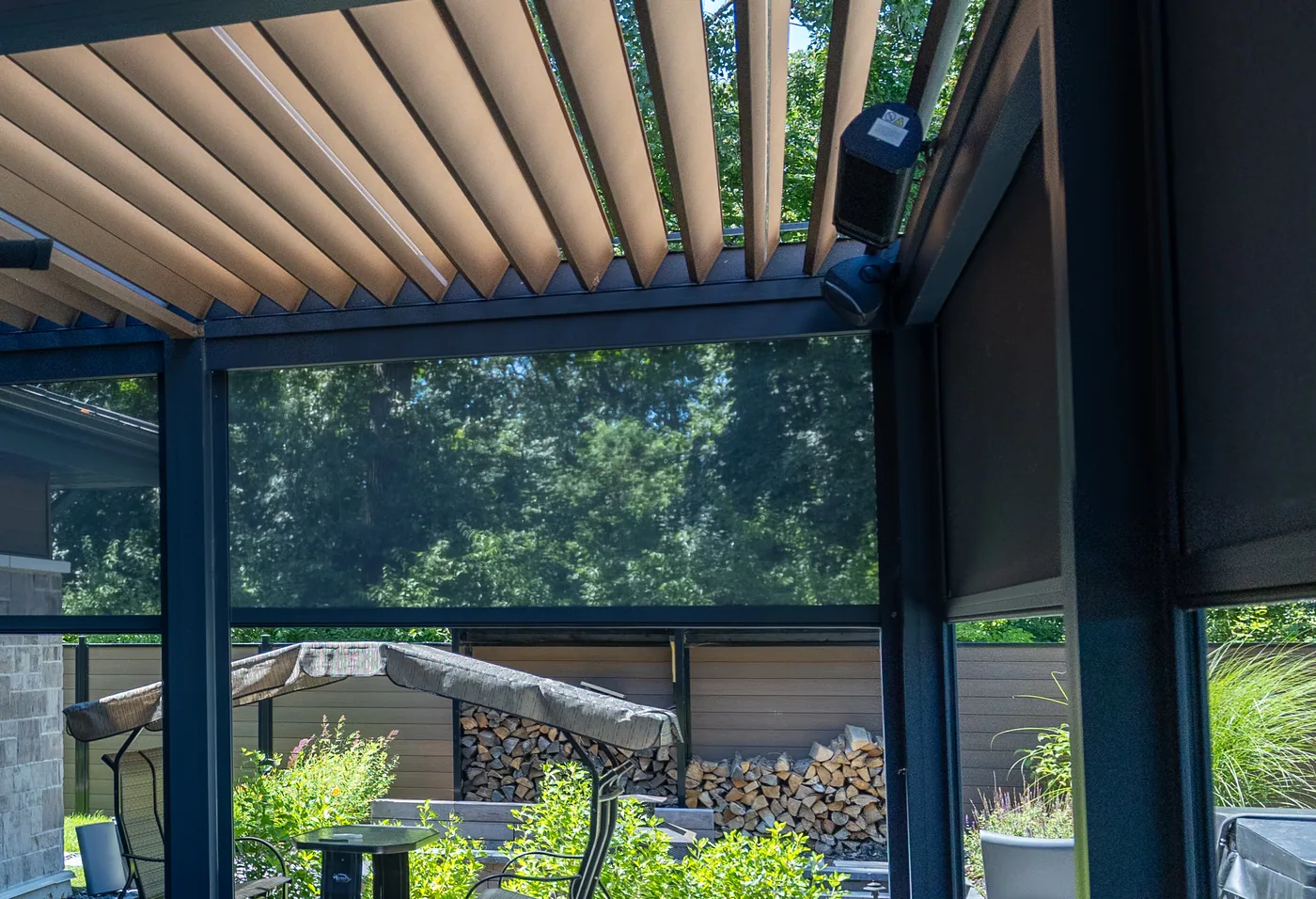 Outdoor shade lowered along the side of the pergola, fixed to the house