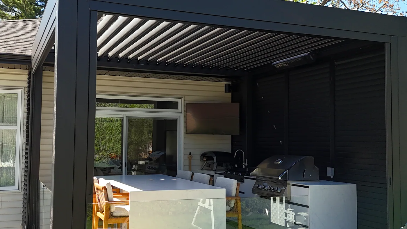 Le soffite de la maison passe sous la toiture de la pergola, au même niveau; le poteau est planté à l’extérieur de la corniche et le mur d’intimité ferme la droite