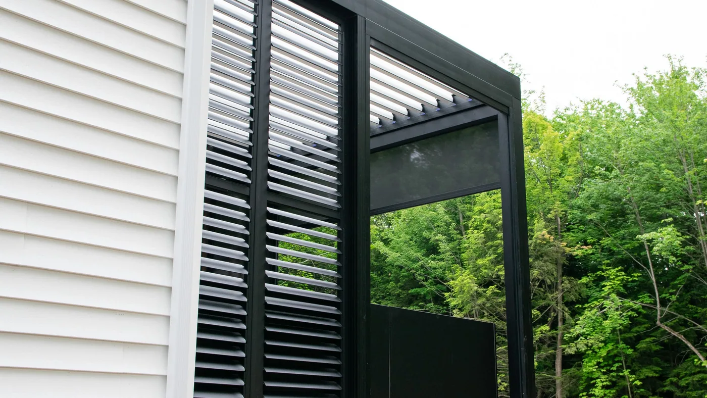 Outdoor kitchen set up in the newly covered space, with shades and a privacy wall