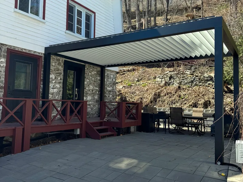 Freestanding Capri pergola with white louvres and a charcoal frame, on the pavers of an ancestral fieldstone home