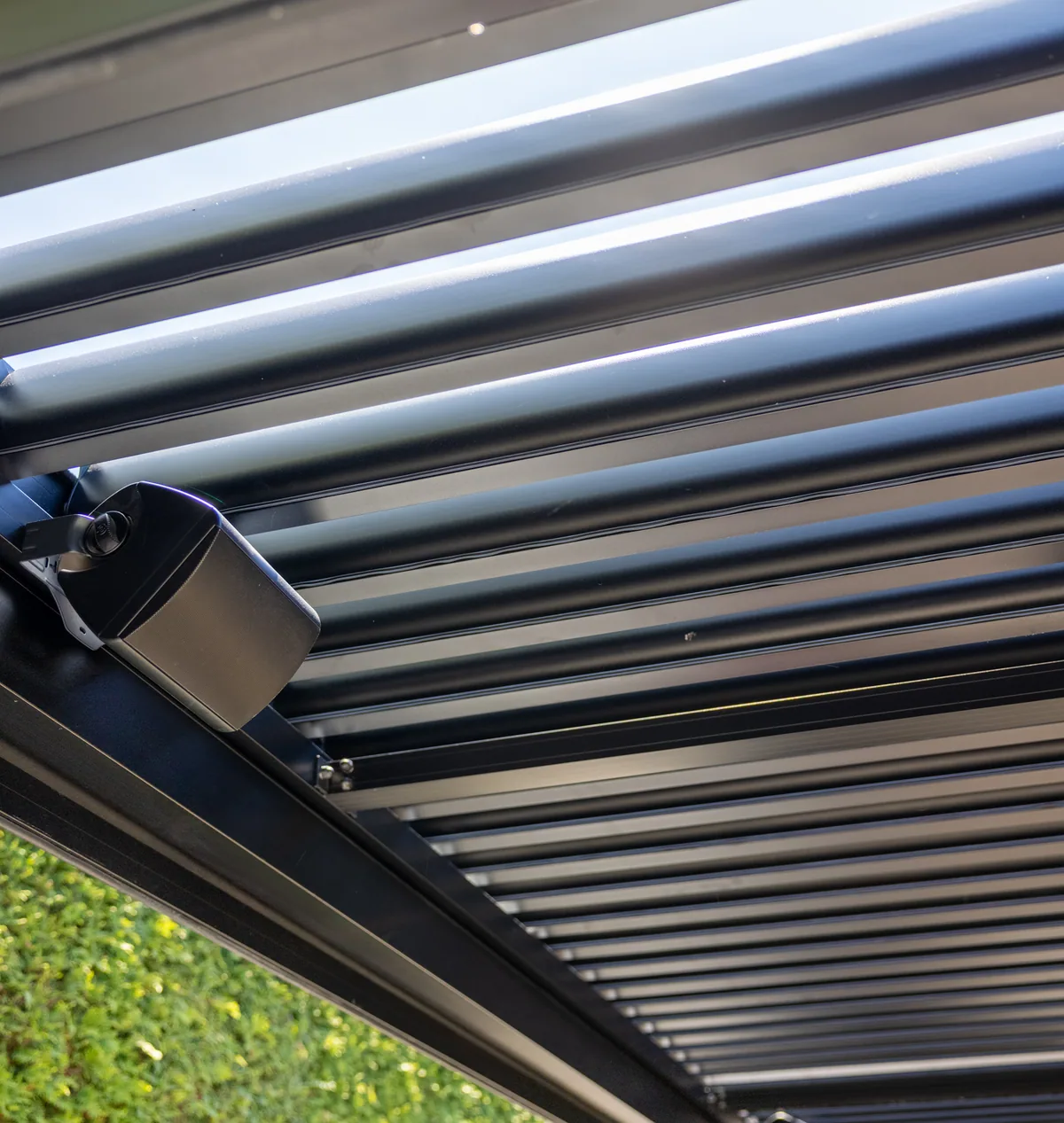 The client’s speaker fixed to the beam, under the roof louvres of the pergola
