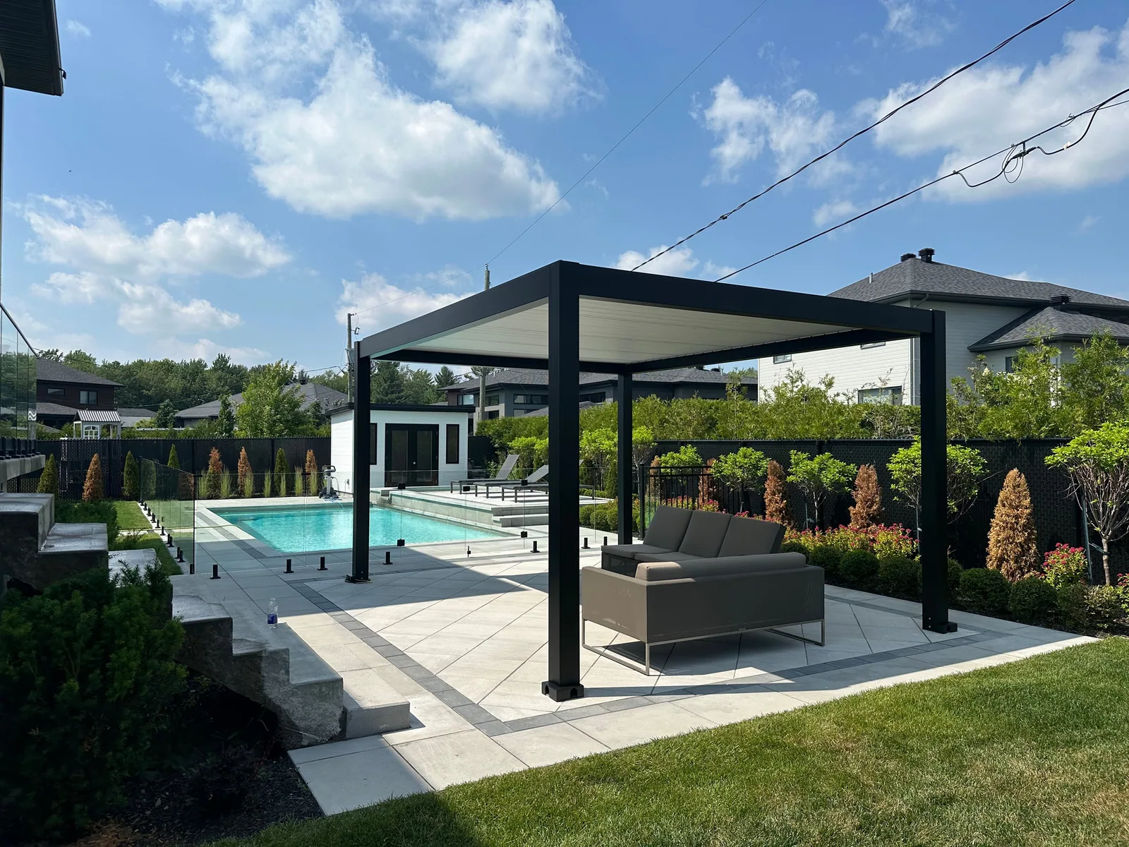 Pergola Provence noire à lames blanches, de style pool house, près de la piscine à Blainville
