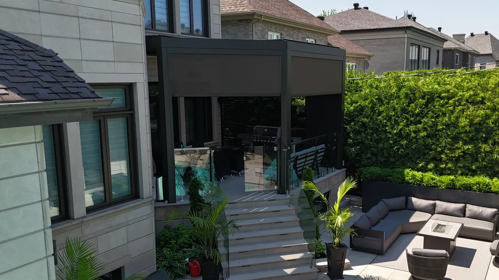 Vue de haut de la pergola de Laval : le cadre, adossé à la maison, est coupé en angle devant la terrasse