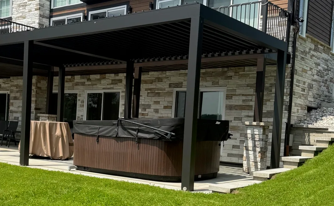 The swim spa under the pergola’s louvred roof, along the stone wall